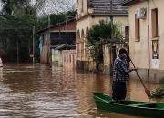 Homem andando de canoa em uma rua completamente alagada 